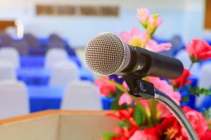 Microphone and podium with flowers.