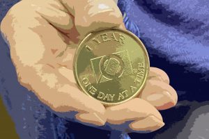 Woman’s hand holding an OA one-year anniversary coin.