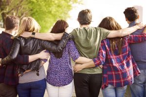 Close group of friends standing arm in arm.