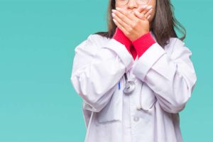 Health care worker covering her mouth with her hands
