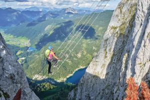 Woman crossing a mountain chasm on a ladder made from cable.